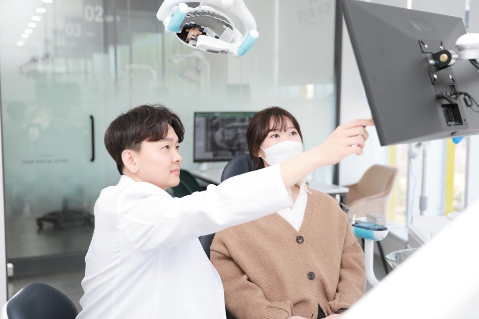 치과의사가 환자에게 모니터 화면을 가리키며 설명하는 모습