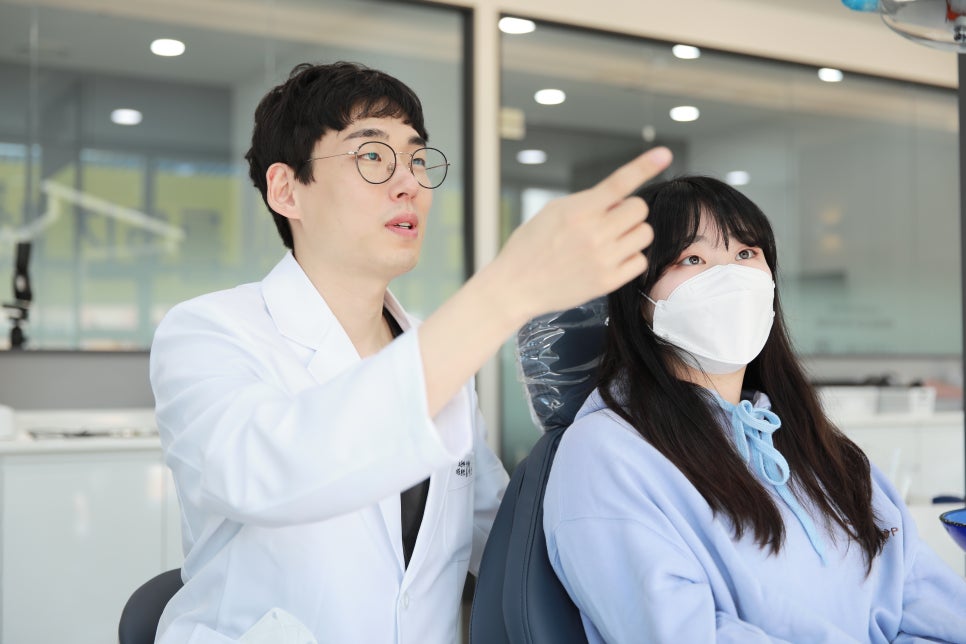 치과 의사가 환자에게 진료 내용을 설명하며 화면을 가리키는 모습