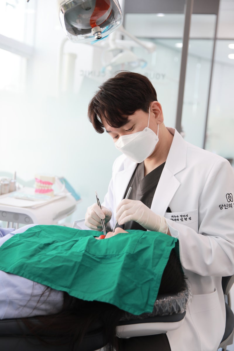 마스크를 쓴 치과의사가 환자의 구강을 진료하는 모습