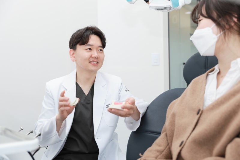 치과의사가 환자에게 치아 모형을 보여주며 설명하는 모습