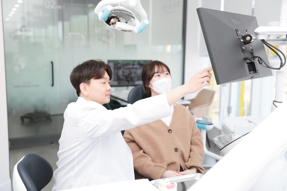 치과 의사가 환자에게 모니터 화면을 가리키며 설명하는 모습