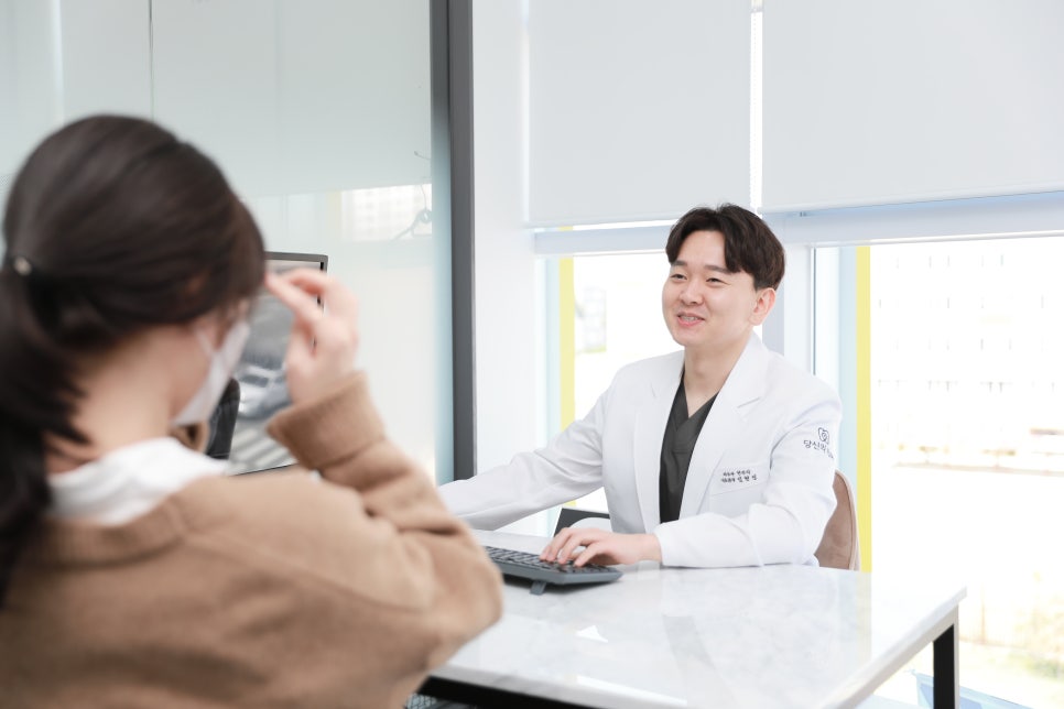 치과 의사가 환자와 마주 앉아 컴퓨터 화면을 보며 상담하는 모습