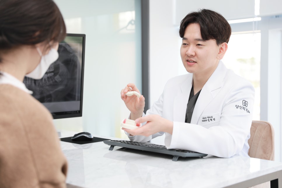 치과 진료실에서 의사가 환자에게 치아 모형을 보이며 상담하는 모습