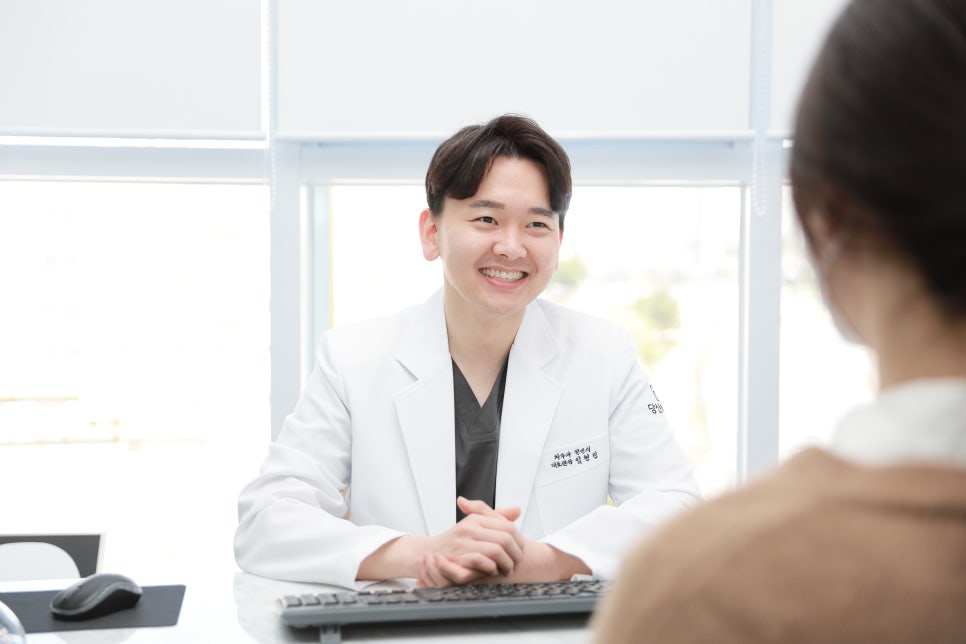 치과 의사가 환자와 마주 앉아 미소 지으며 상담하는 모습