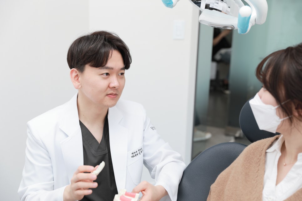 치과 진료실에서 의사가 환자에게 치아 모형을 보이며 설명하는 모습