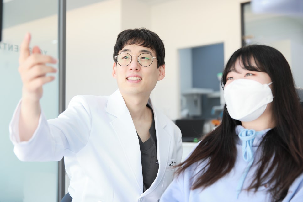 치과 의사가 환자에게 진료 내용을 설명하며 화면을 가리키는 모습