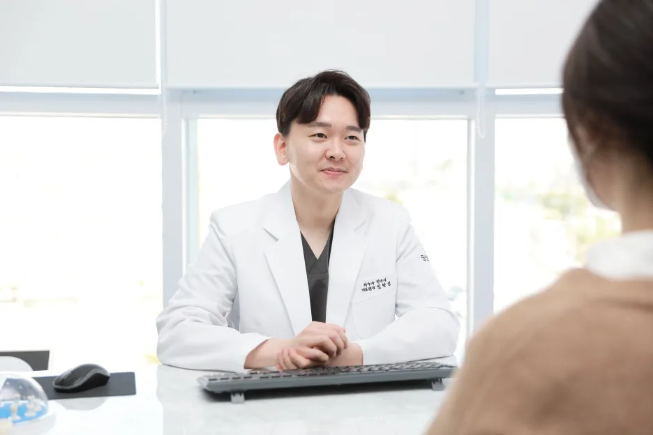 치과 의사가 환자를 마주보고 앉아 미소 지으며 상담하는 모습